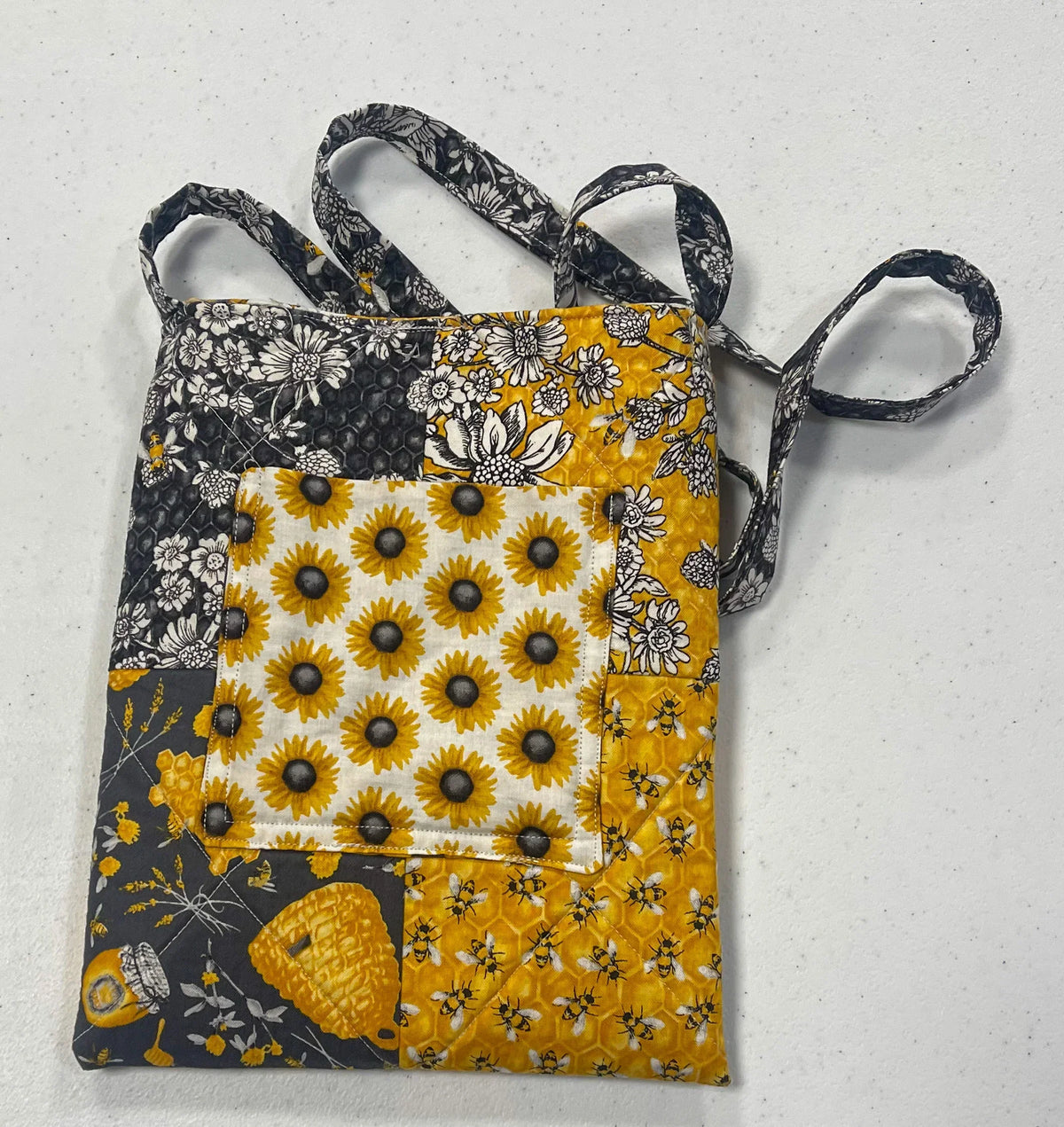 Quilted crossbody bag with black and yellow floral fabric and adjustable strap