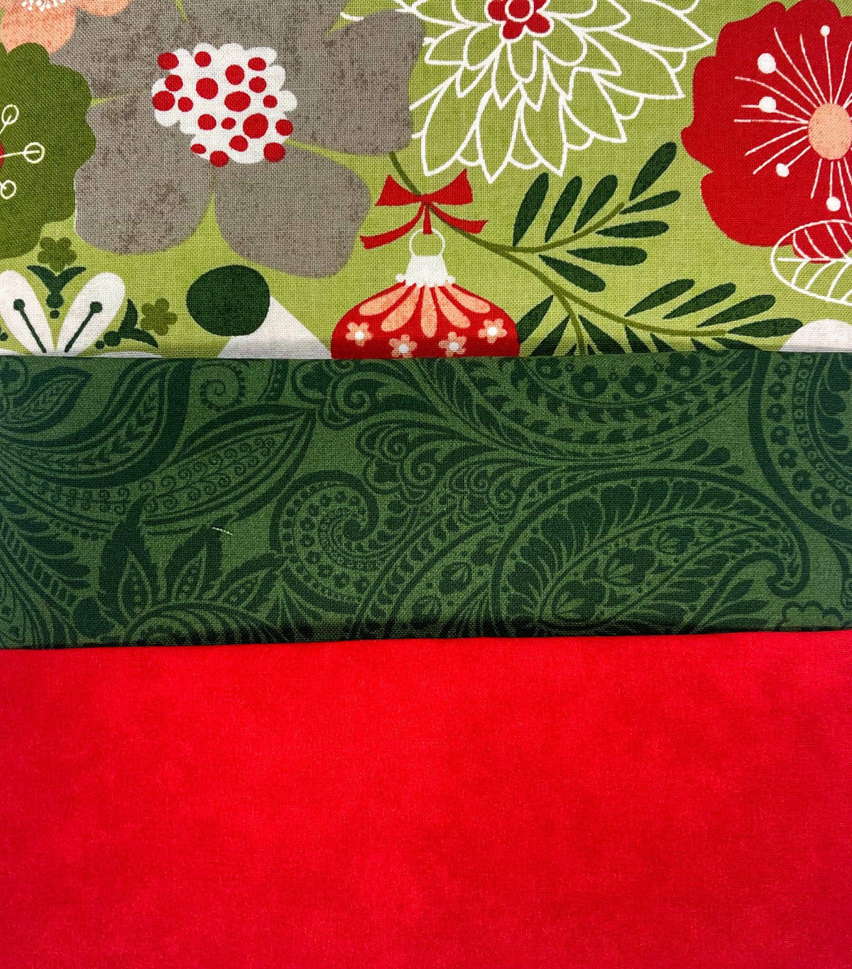 Holiday quilt fabric bundle with red solid panels and green paisley with floral prints