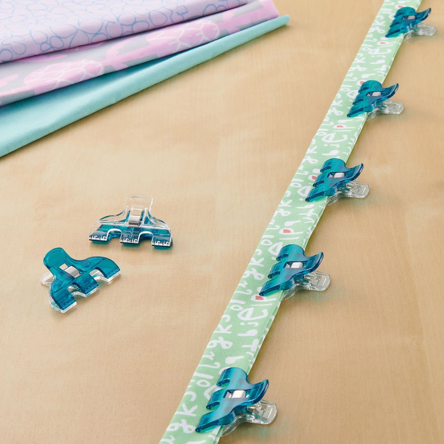 Triple wide Wonder Clips securing quilt strips, teal clips on fabric