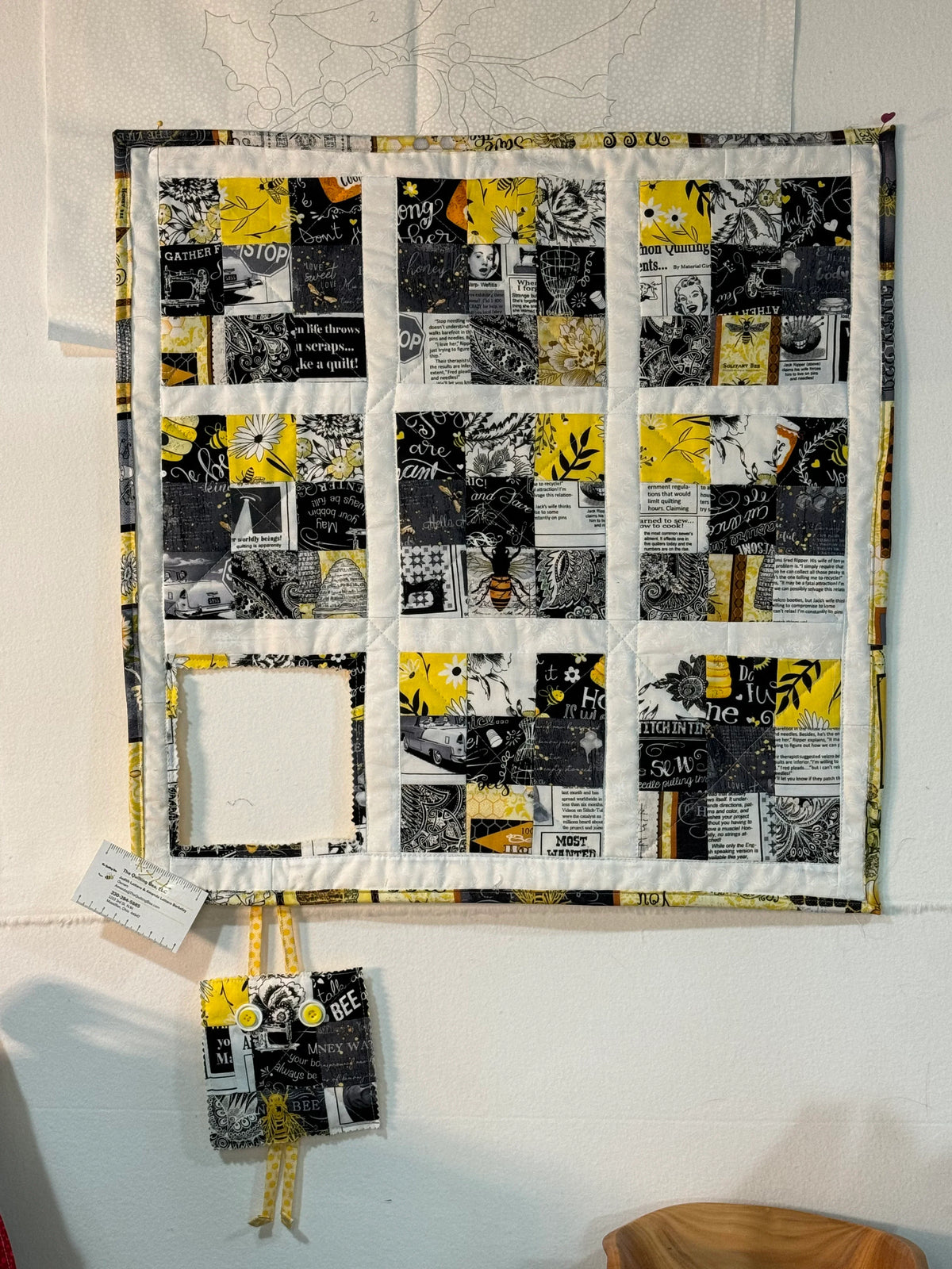 Patchwork wall hanging with black, white, and yellow 9-panel blocks, bordered in yellow