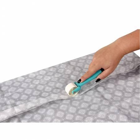 Seam roller tool with turquoise handle rolling on light gray patterned fabric