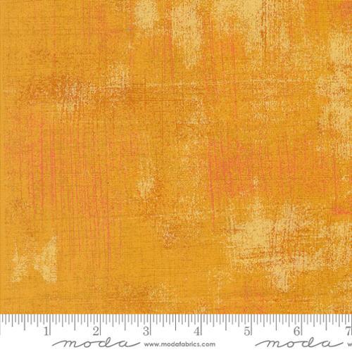 Mustard-orange textured quilting fabric with mottled grunge pattern and light speckling