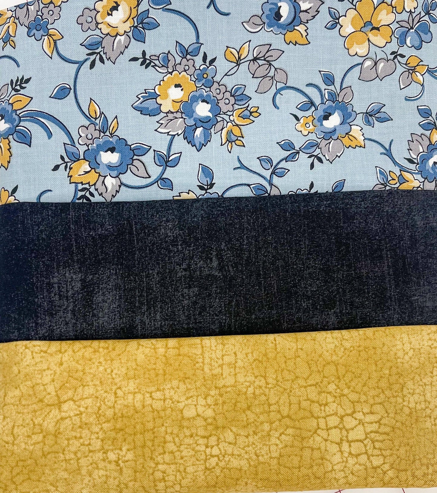 Quilt fabric bundle with blue floral, black solid, and yellow textured yardage