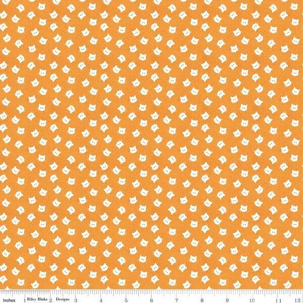 Orange fabric with repeating small cat face pattern, white dots and shapes