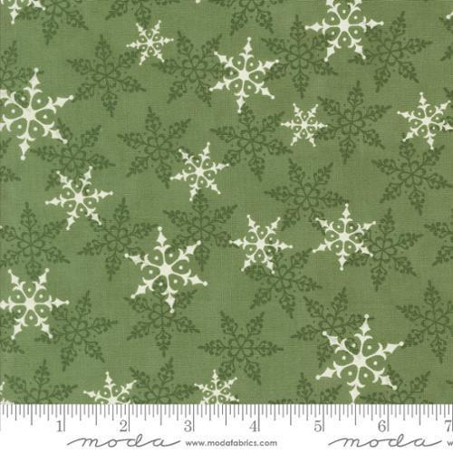 Green printed cotton fabric with scattered white snowflake and pine-like motifs