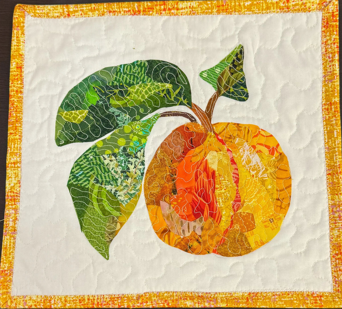 Peach and leaf applique collage quilt block with orange, yellow, and green shapes