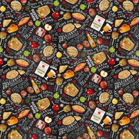 Black harvest-themed quilting fabric with scattered fruit, stars, and text motifs