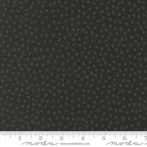 Cotton fabric swatch with small light dots on dark gray background