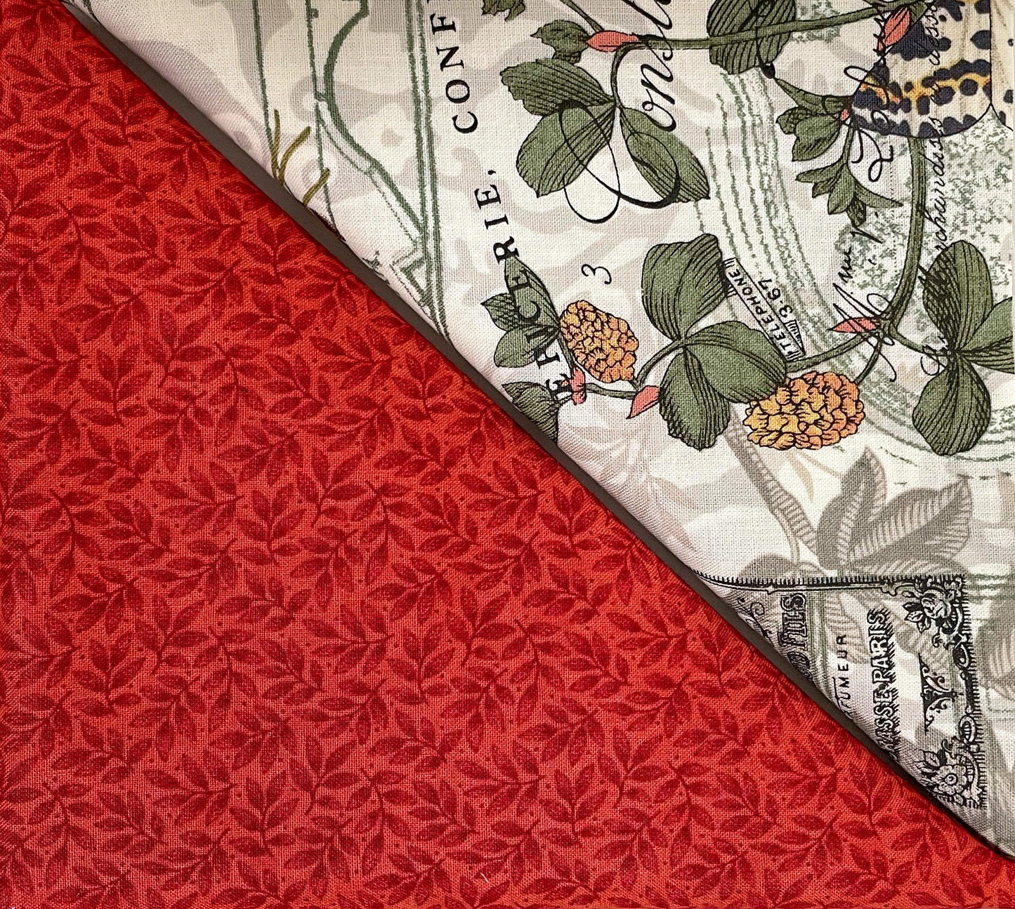 Red table runner with woven leaf pattern and cream floral border print