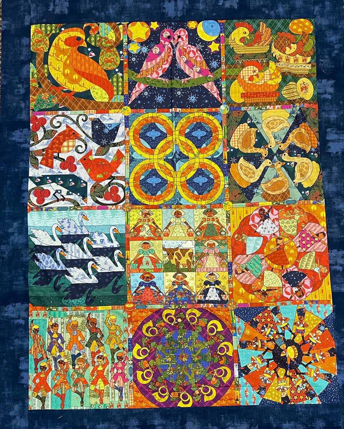 Christmas fabric panel in dark blue with birds, circles, and festive figures in squares