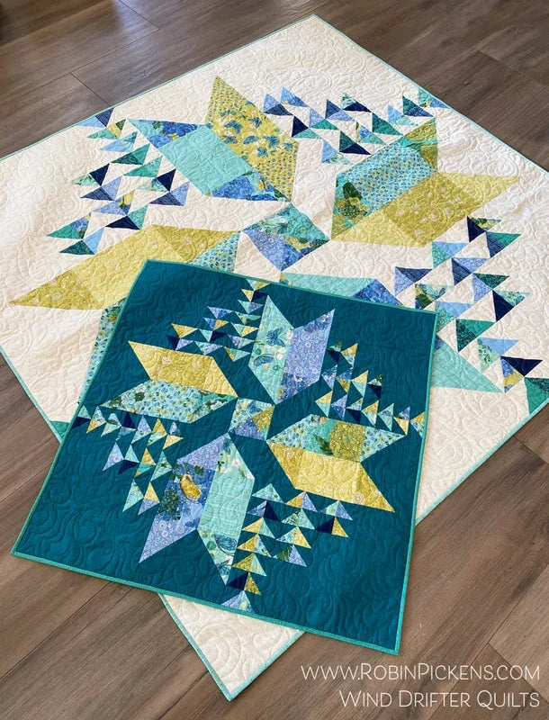 Completed quilt with white ground and blue, teal, and yellow pinwheel blocks
