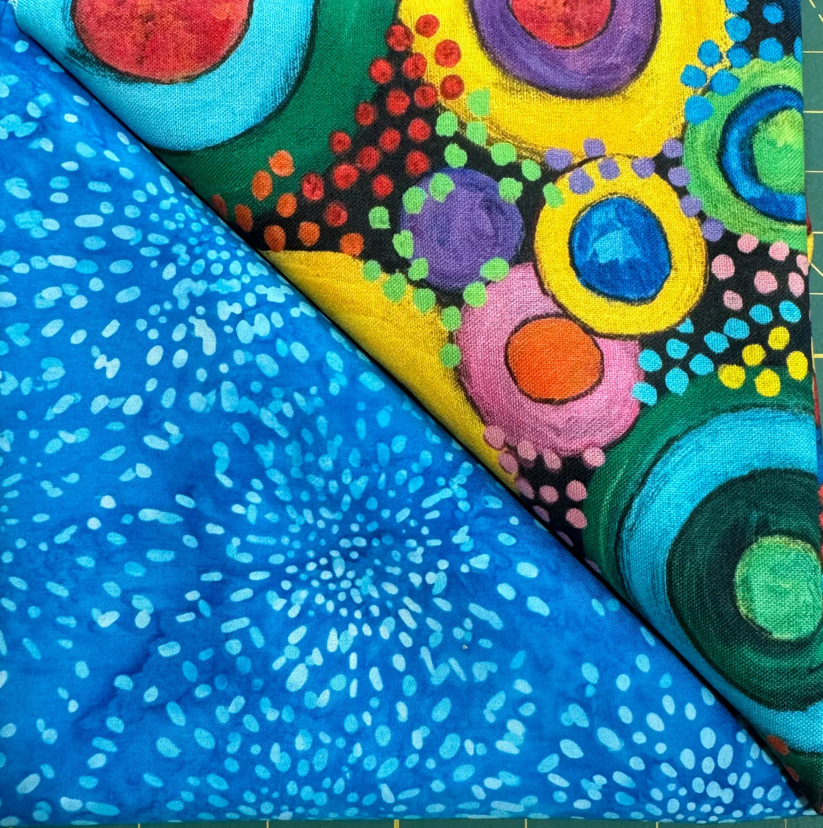 Table runner fabric with blue batik dots and multicolor circle pattern, folded edge