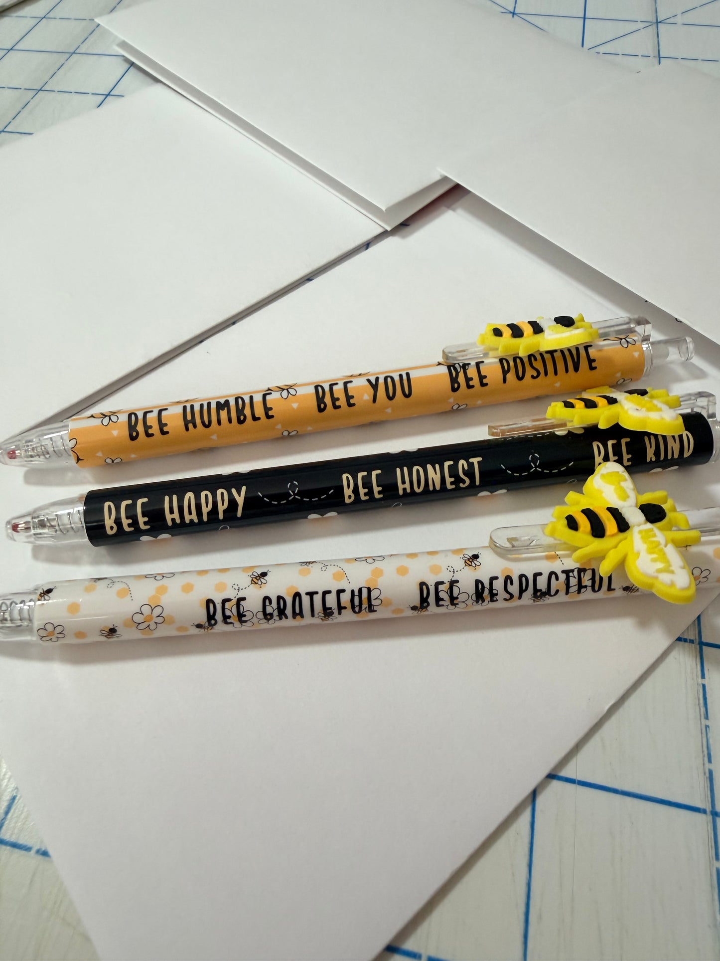 Bee-themed pens with yellow-and-black bee decals and motivational sayings on barrels