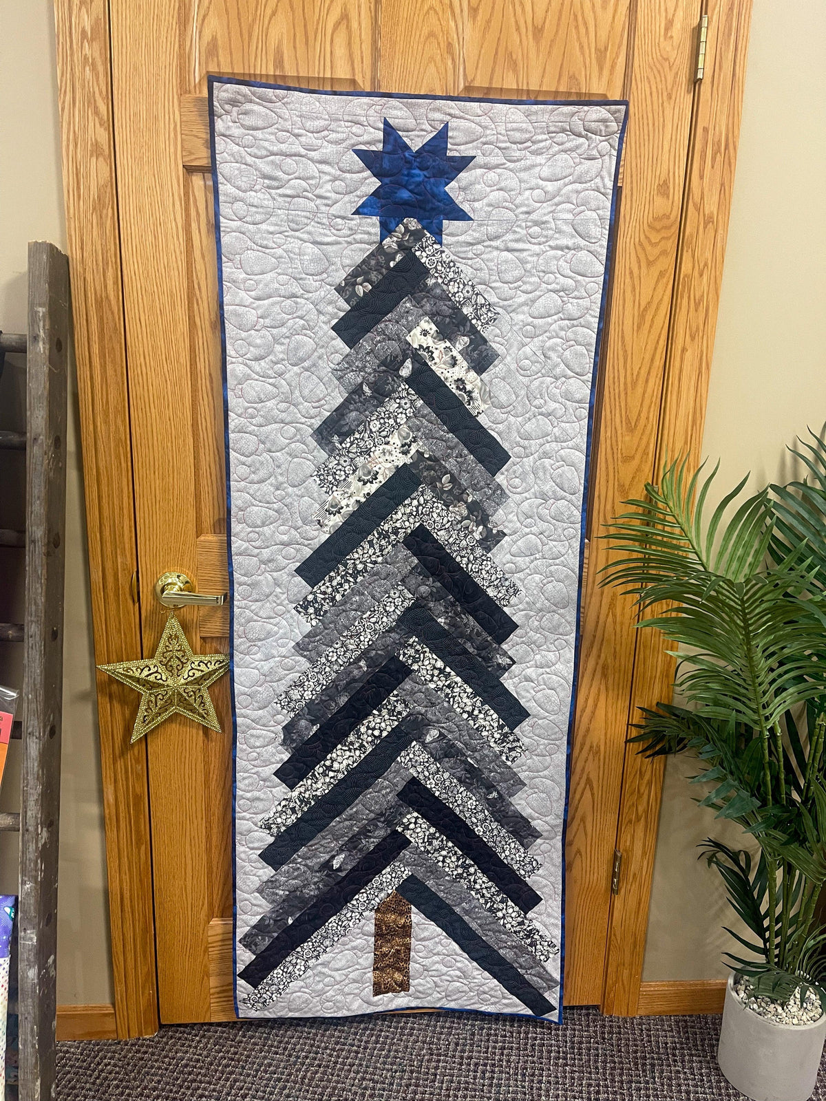 Navy and white tree braid quilt with blue star topper and layered striped fir design