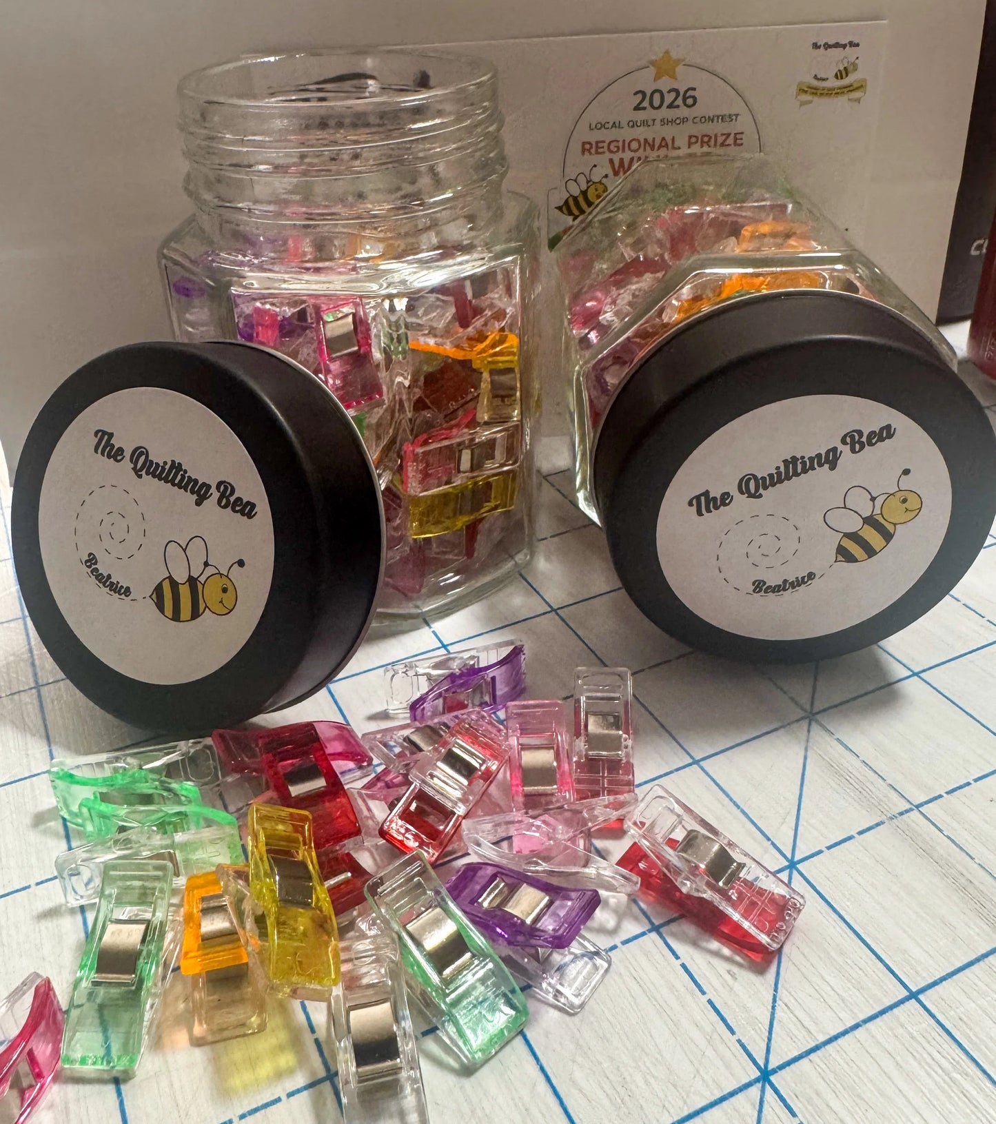 Multi colored 1-inch binding clips in clear jars, with black lids and loose clips