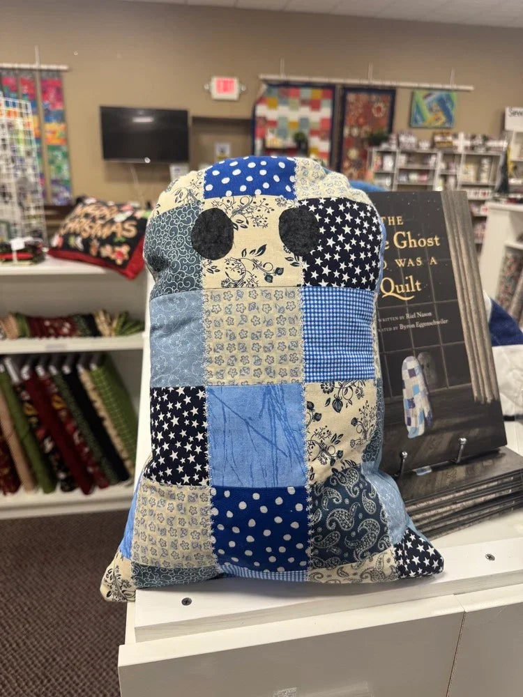 Quilt pillow shaped like a little ghost, patchwork blue, cream, and dark stars front.