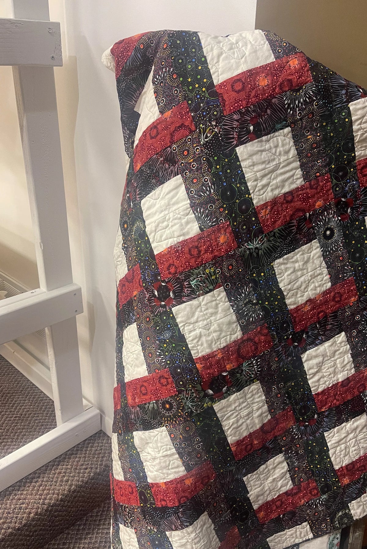 Patchwork quilt with red and white blocks on dark gray background, folded over