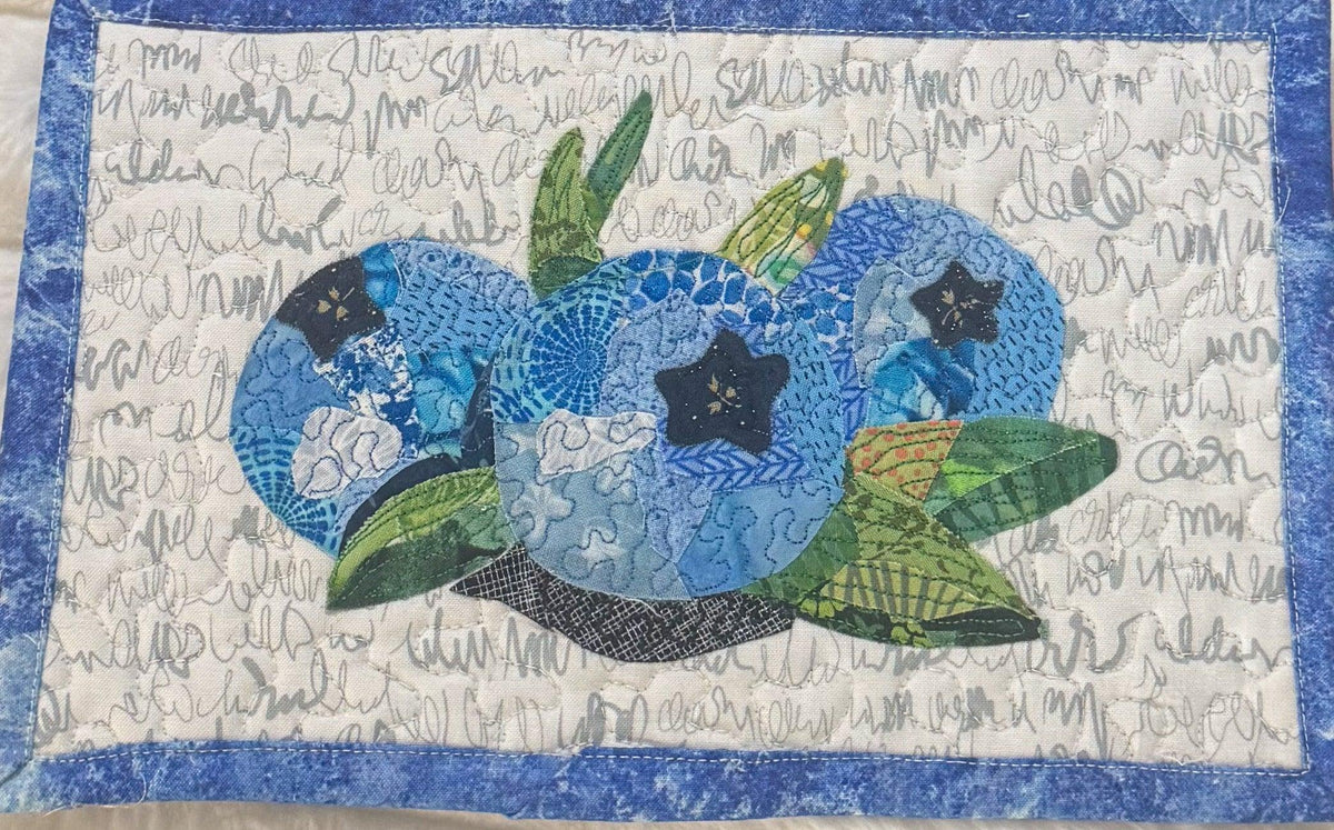Mini collage project featuring blue blueberry shapes with green leaves on light background