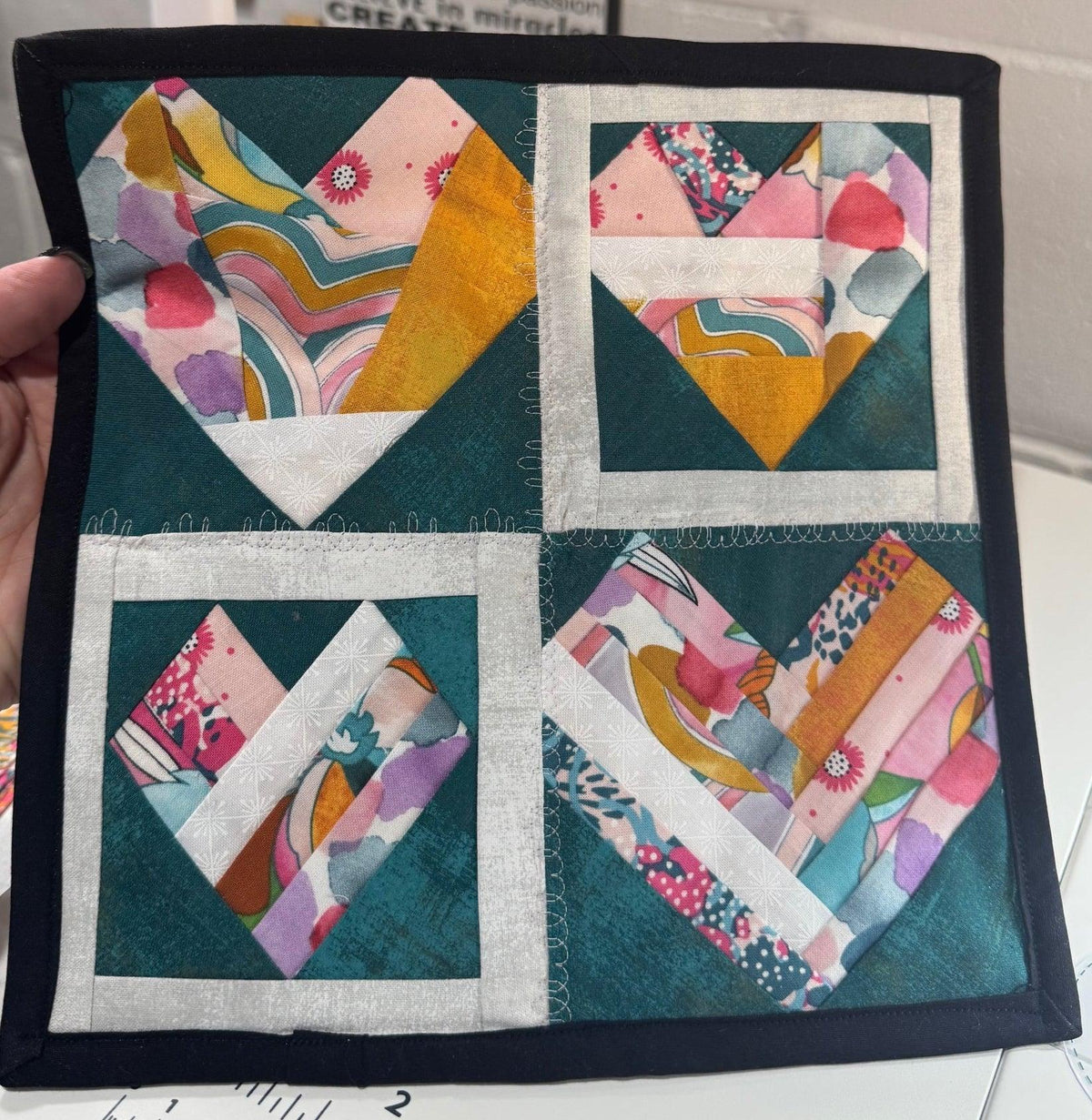 Quilt top with colorful heart block patchwork squares on teal and white borders
