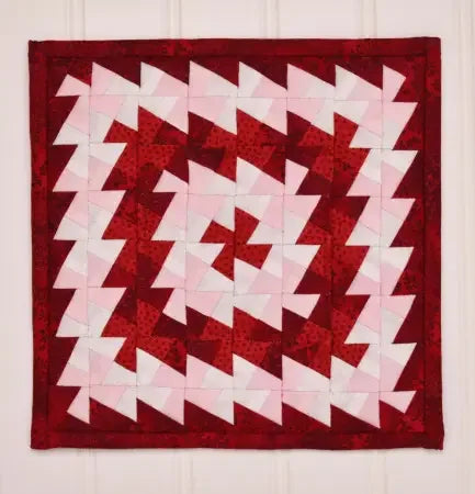 Red and white pinwheel quilt block with zigzag patchwork, square