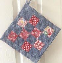 Quilted potholder with red and pink diamond patchwork on blue square fabric