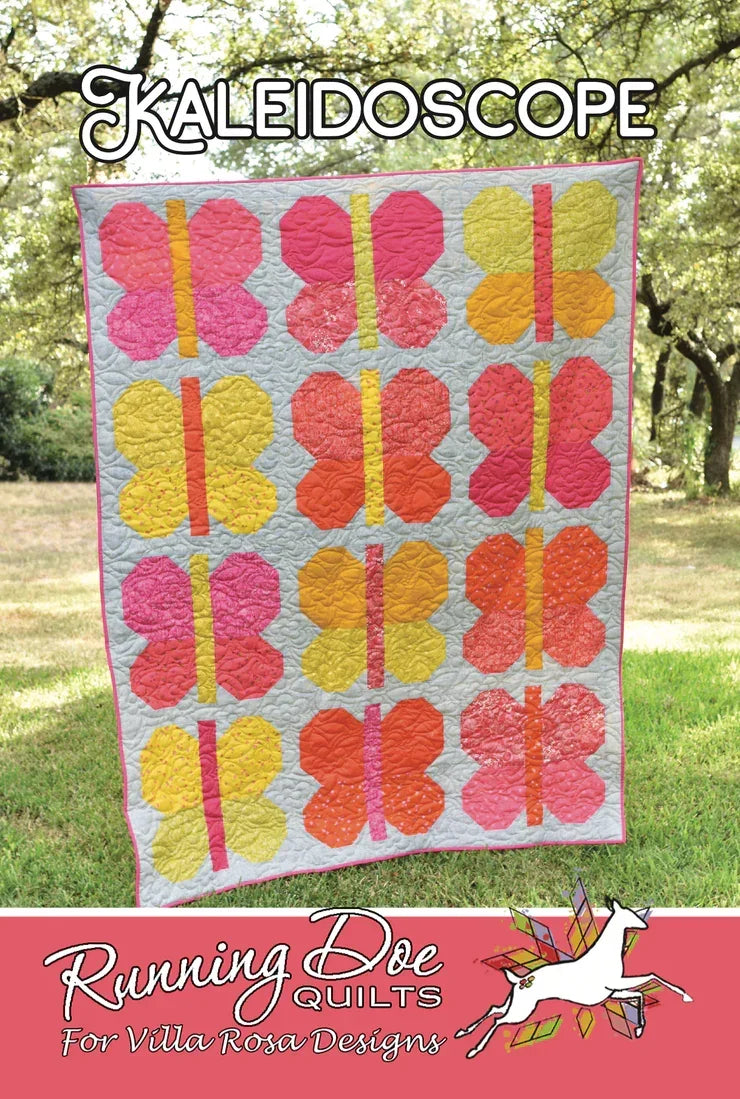 Kaleidoscope quilt with pink, yellow, orange, and blue geometric blocks on light backing