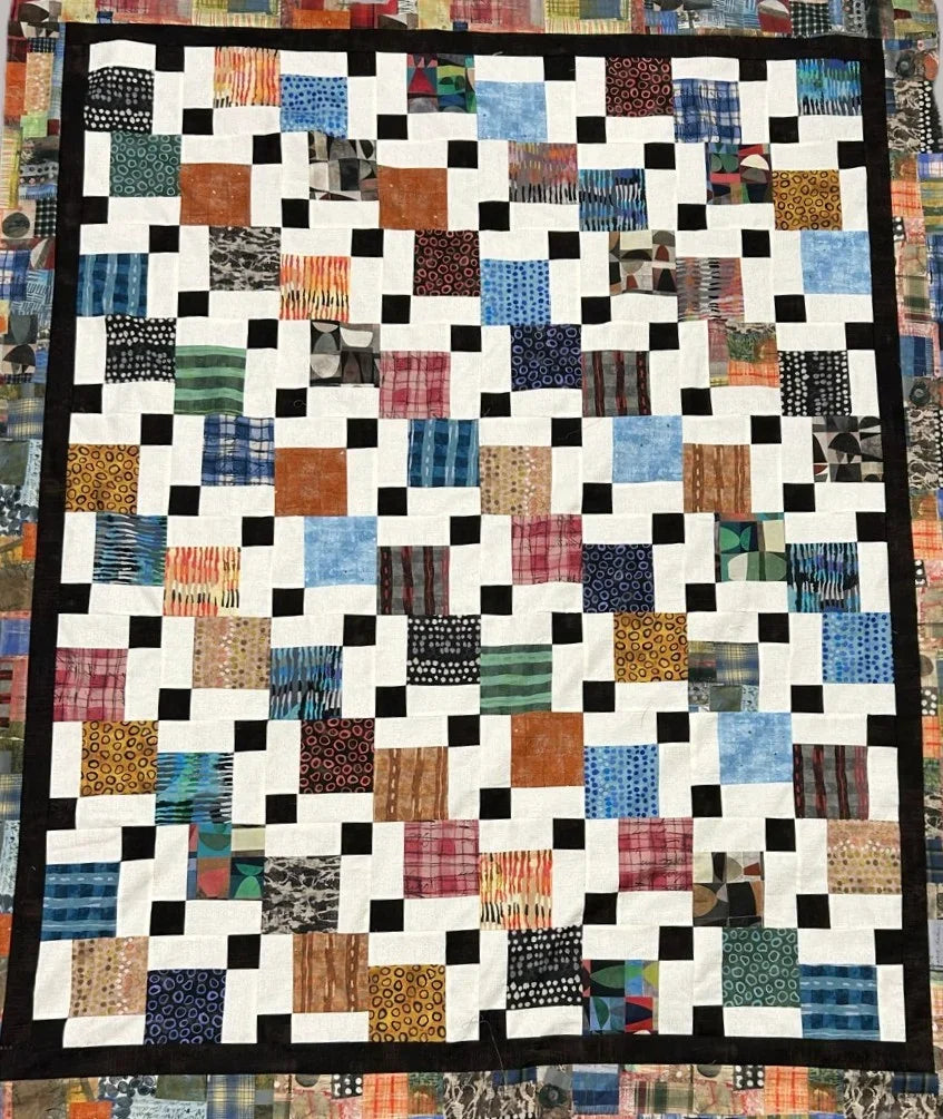 Patchwork quilt with disappearing nine-patch squares in multicolor prints and cream