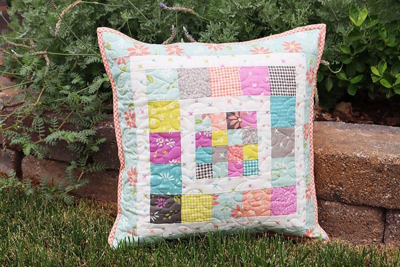 Quilted patchwork pillow cover with pastel blocks and floral accents, square shape