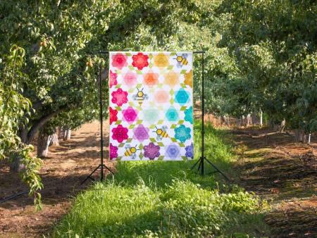 Multicolor quilt on display, featuring floral geometric blocks and honeycomb motifs