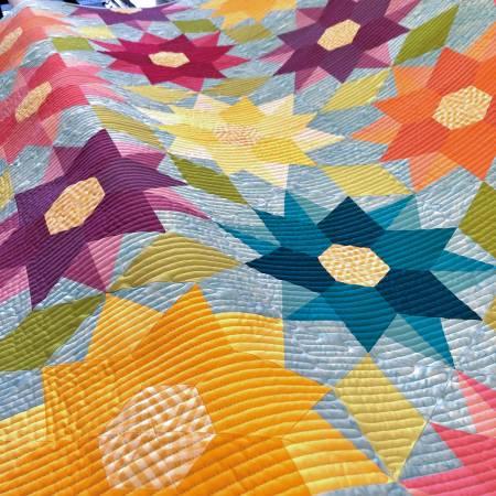 Close-up of quilted geometric dahlia blocks in bright multicolor fabric and stitching.