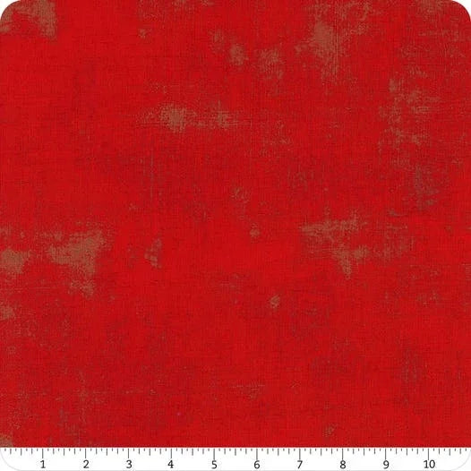 Red printed fabric yardage with distressed speckle pattern, close-up view