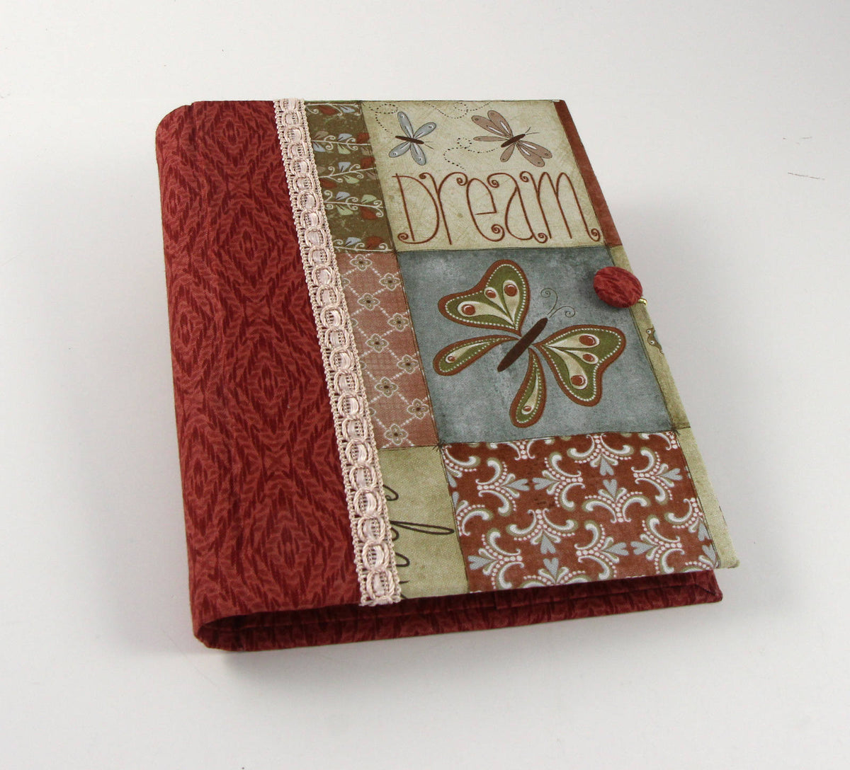 Fabric journal cover with red textured panel, lace trim, and decorative butterfly patch.