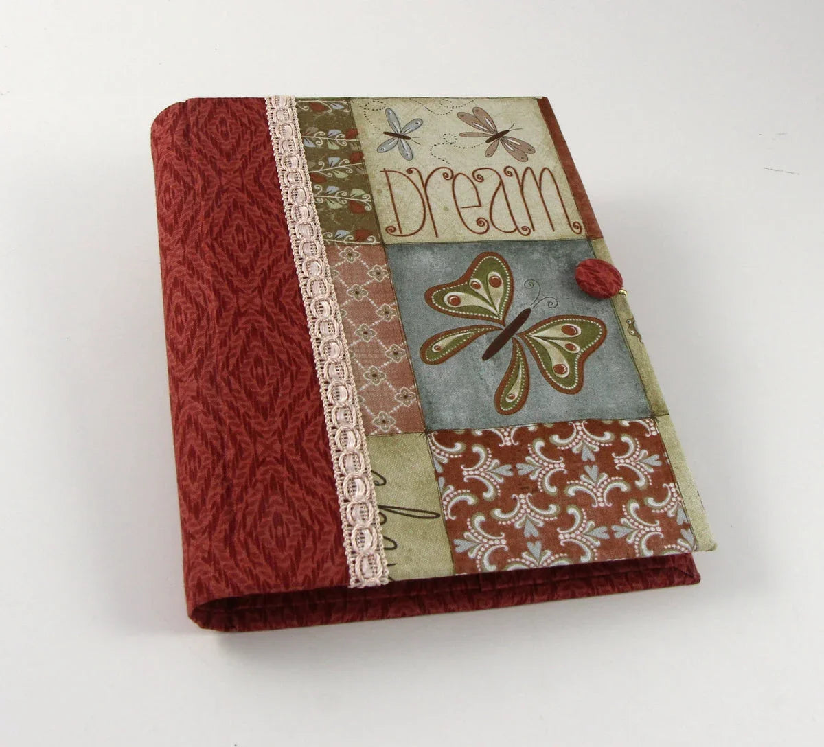 Fabric journal cover with red textured panel, lace trim, and decorative butterfly patch.