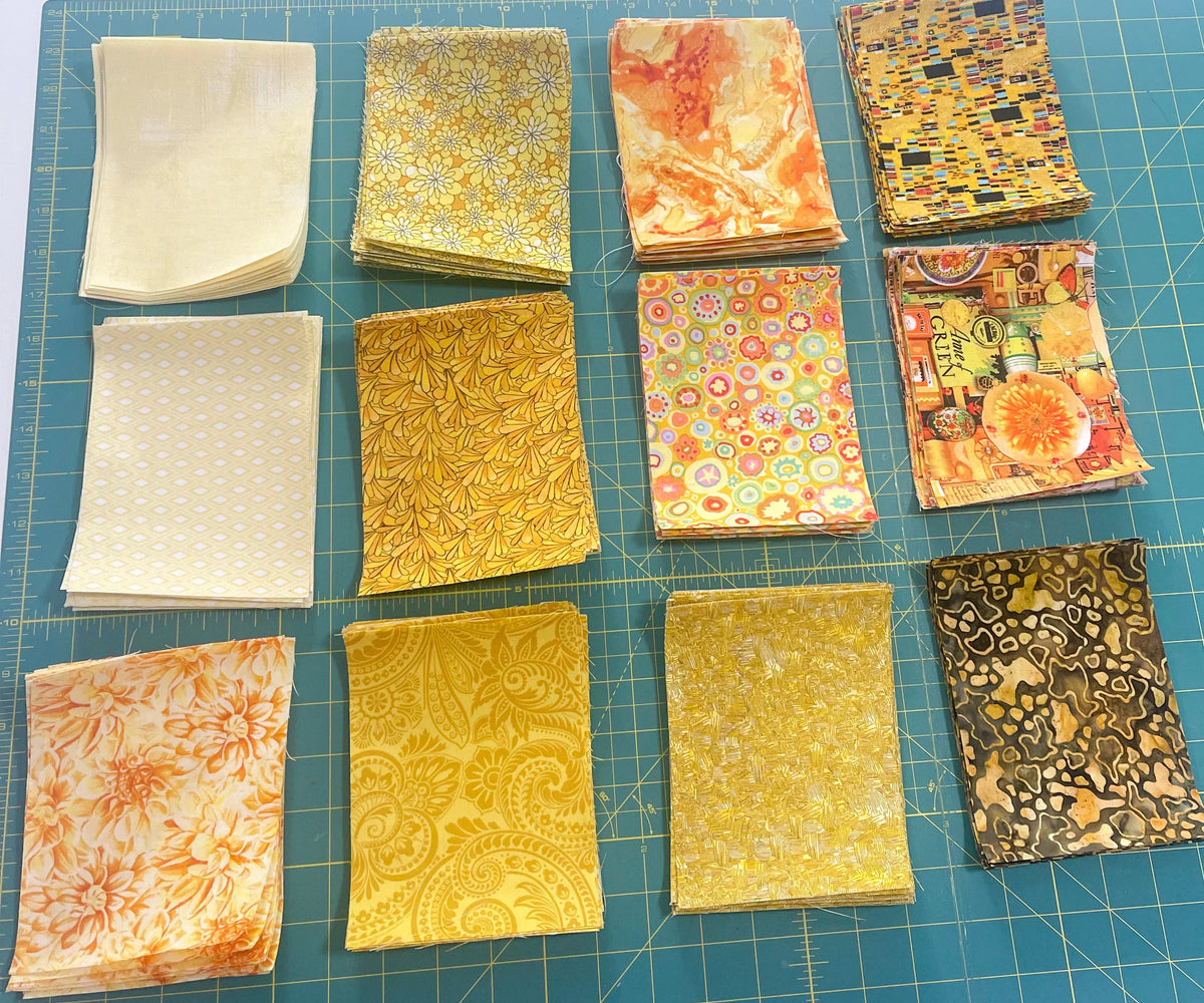 Yellow fabric square bundle with assorted floral and abstract prints, folded in stacks