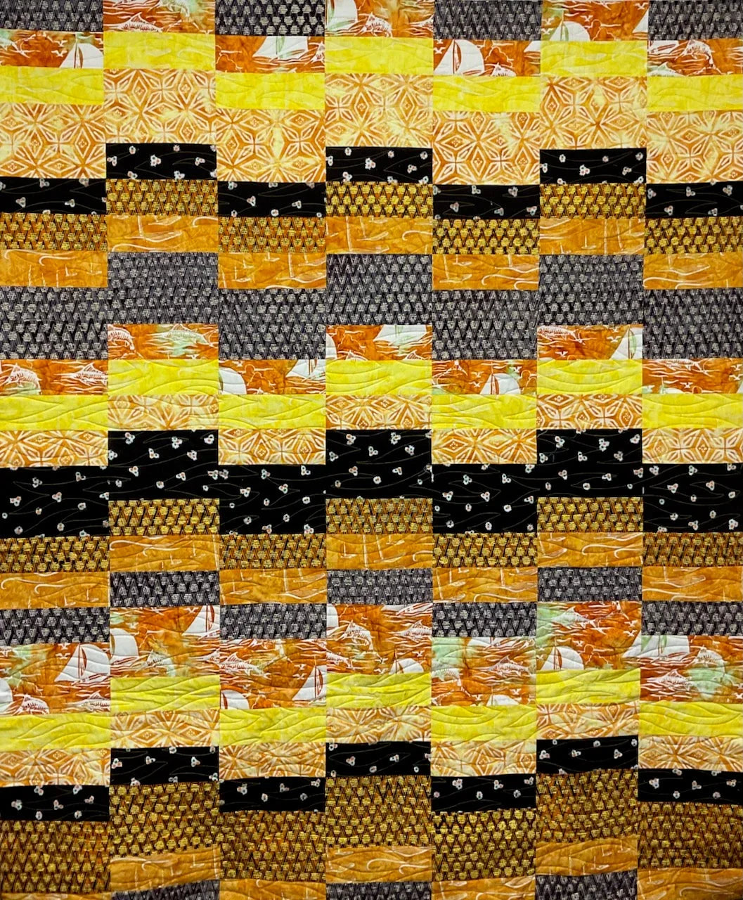 Cobblestones quilt pattern fabric blocks in orange, black, and green with patchwork layout