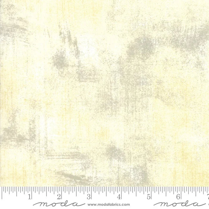 Cream grunge fabric with subtle yellow tint and mottled texture, visible selvedge and ruler scale