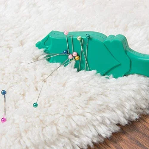 Teal magnetic pin wand placing metal pins into fabric pile