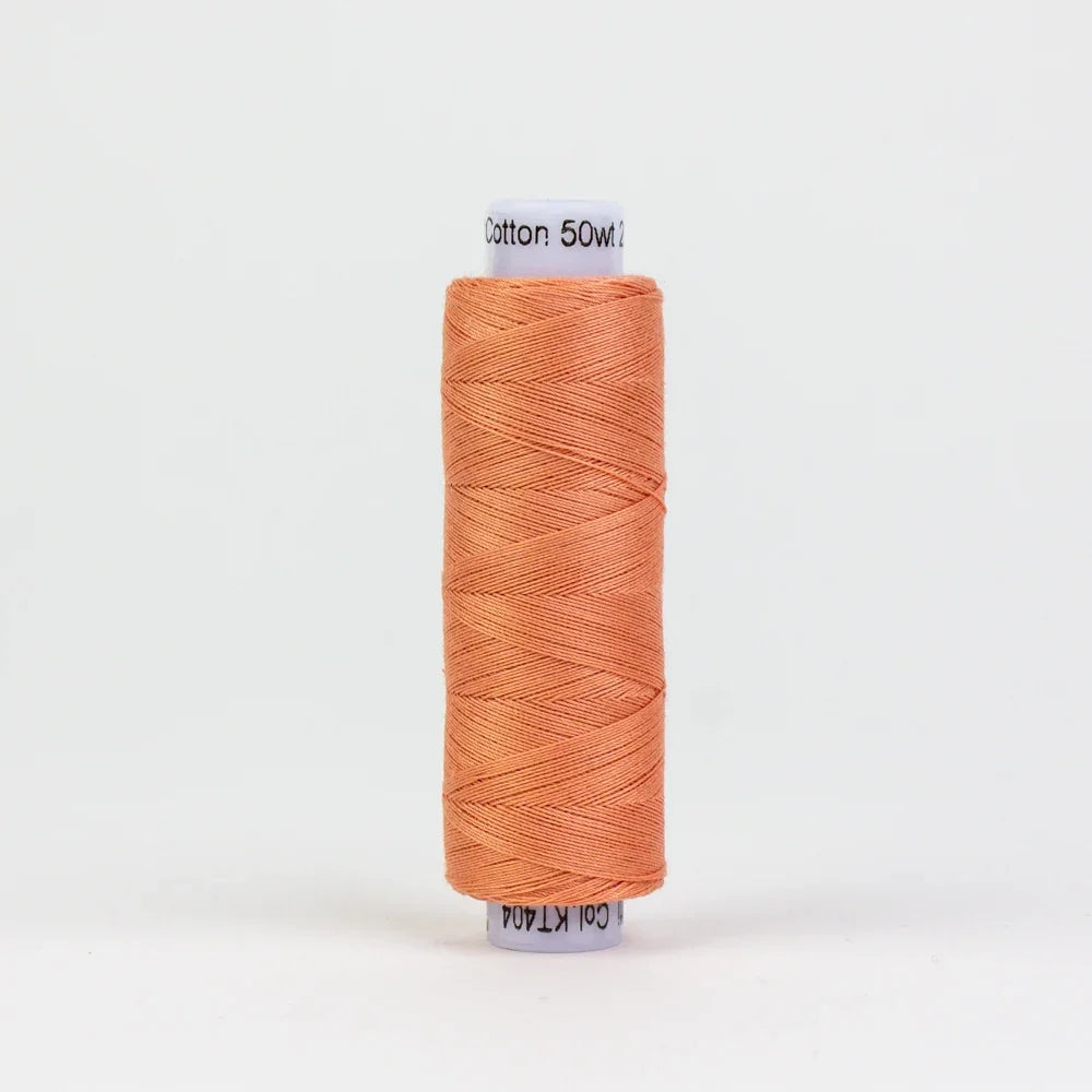 Cotton yarn spool in coral orange, neatly wound on a round bobbin