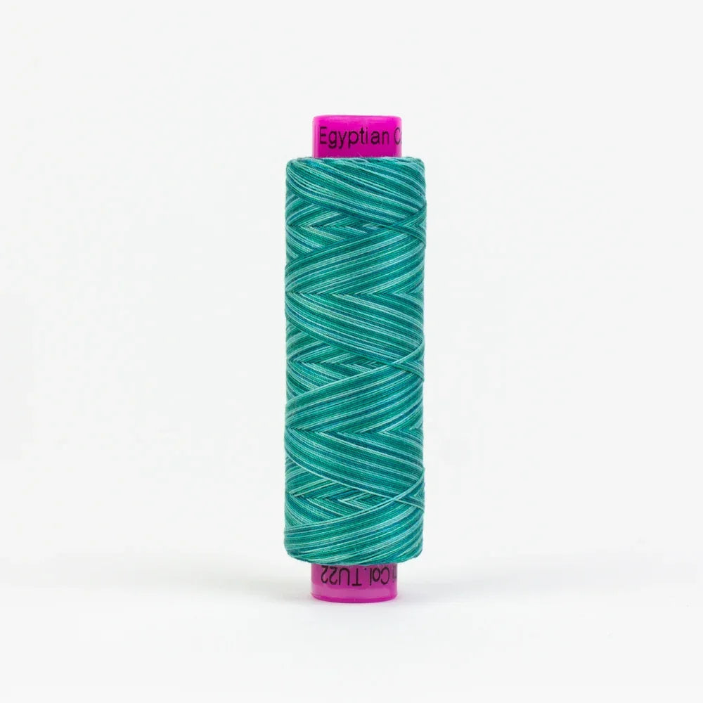 Peacock yarn spool with teal green thread wound on spool, purple label