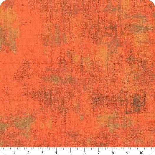 Abstract grunge fabric swatch in orange tones with distressed pattern