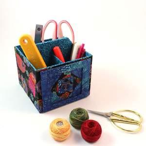 Blue fabric photo caddy with patchwork front and side handles, open interior for photos.