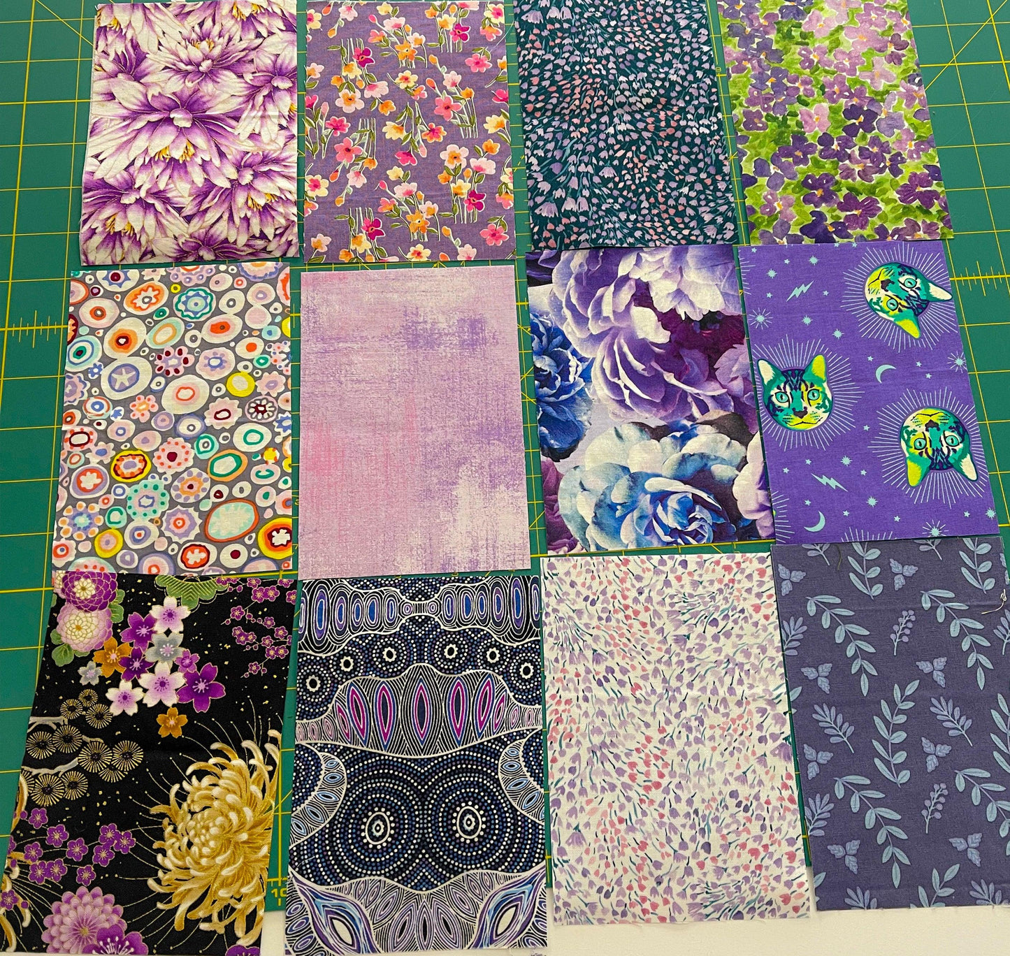 Purple fabric square assortment with floral prints and coordinating patchwork pieces