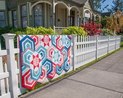 Patchwork quilt with red, white, blue and teal geometric hexagon blocks on display