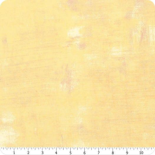 Textured light yellow fabric swatch with subtle speckles and weave texture
