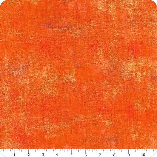 Orange metallic grunge fabric with distressed lighter shapes and mottled texture