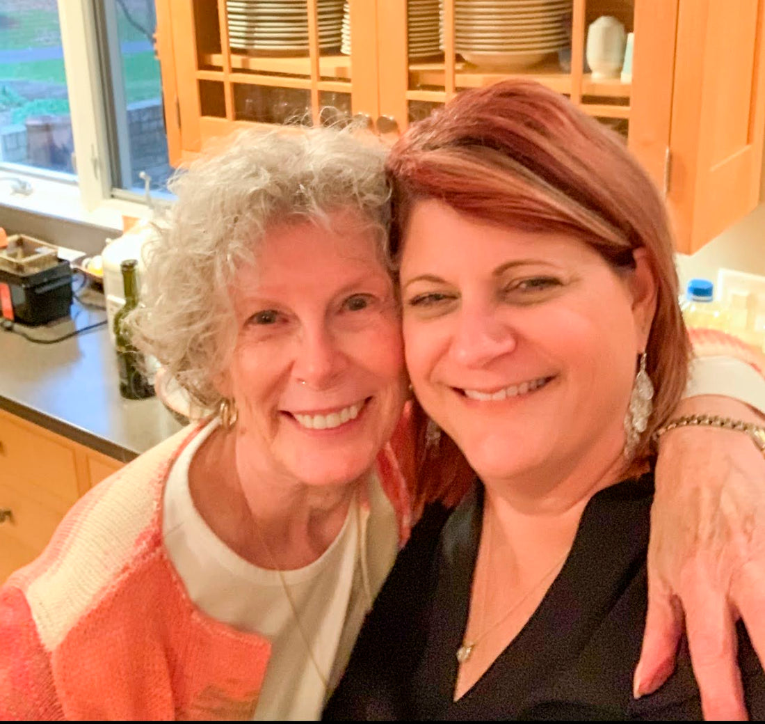 Two smiling women posing closely together in a home kitchen setting.