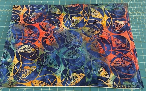 Colorful batik cotton fabric featuring an intricate butterfly and vine pattern.