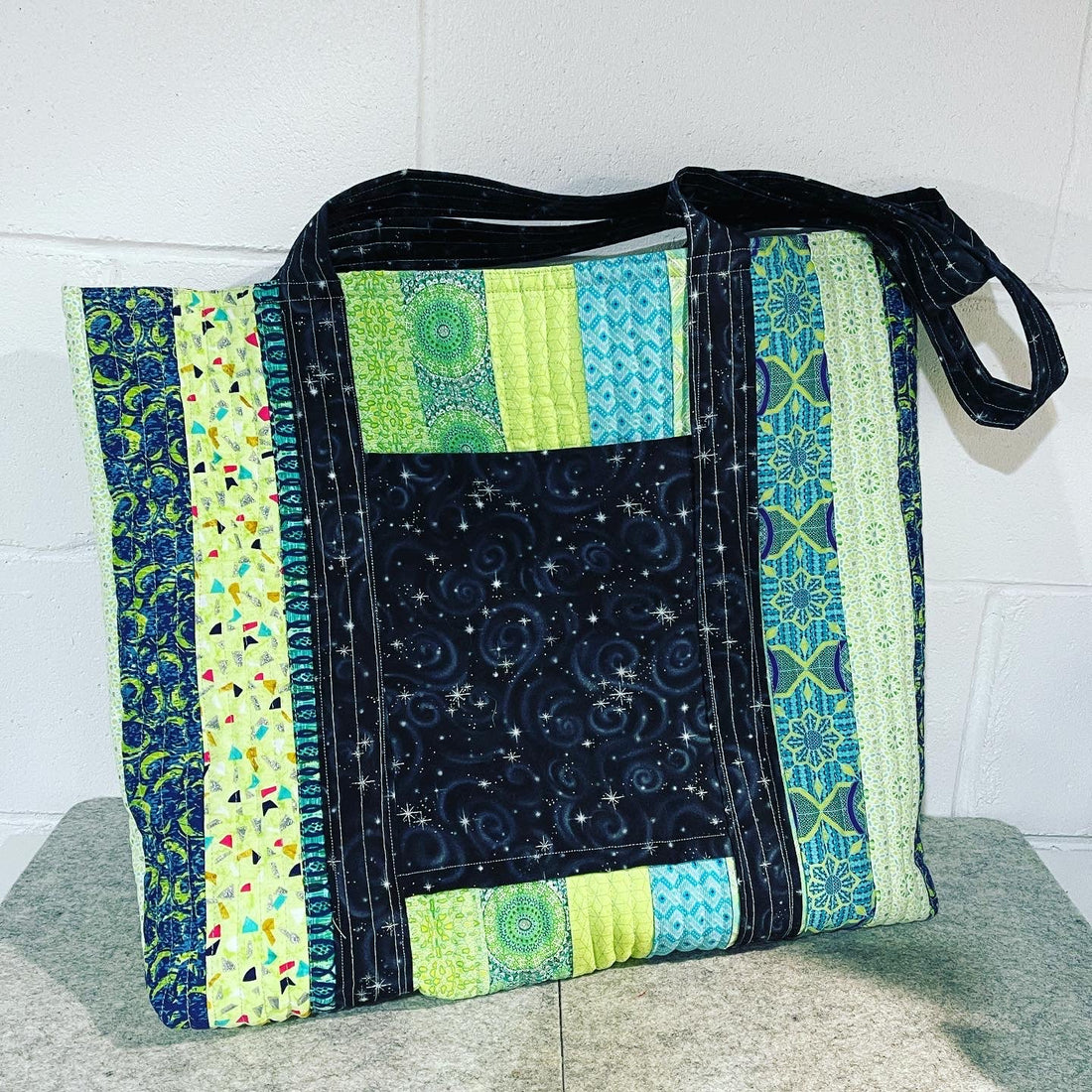 Handmade quilted tote bag featuring multi-colored geometric and celestial fabric patterns.