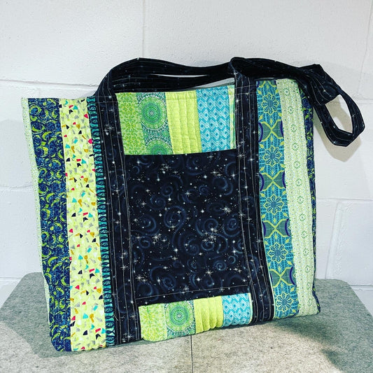 Handmade quilted tote bag featuring multi-colored geometric and celestial fabric patterns.