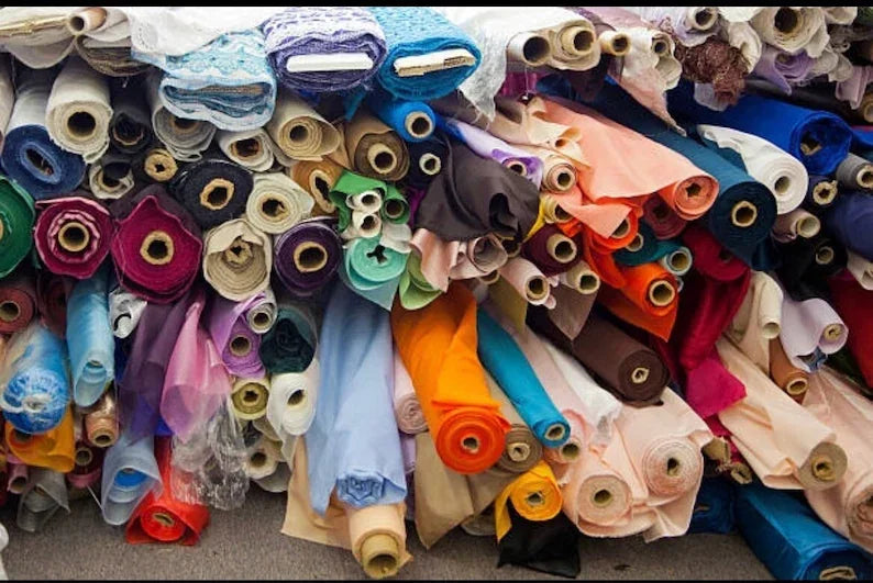 A large assortment of colorful fabric bolts and textile rolls stacked in a quilt shop.